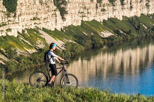 girl standing with bicycle on a background of cliff