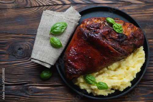Bilde på lerret Baked pork knuckle with mashed potato in a rustic wooden setting