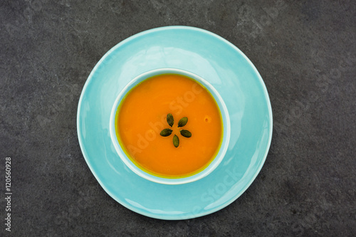 Cream of pumpkin soup with pumpkin seeds on black stone table. Vegetarian food.