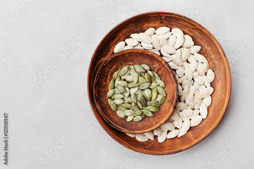 Pumpkin seeds in a clay bowl on gray background top view