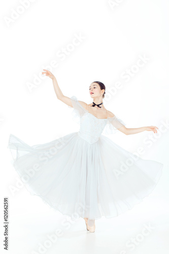 Ballerina in white dress posing on pointe shoes  studio background.