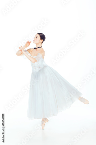Ballerina in white dress posing on pointe shoes  studio background.
