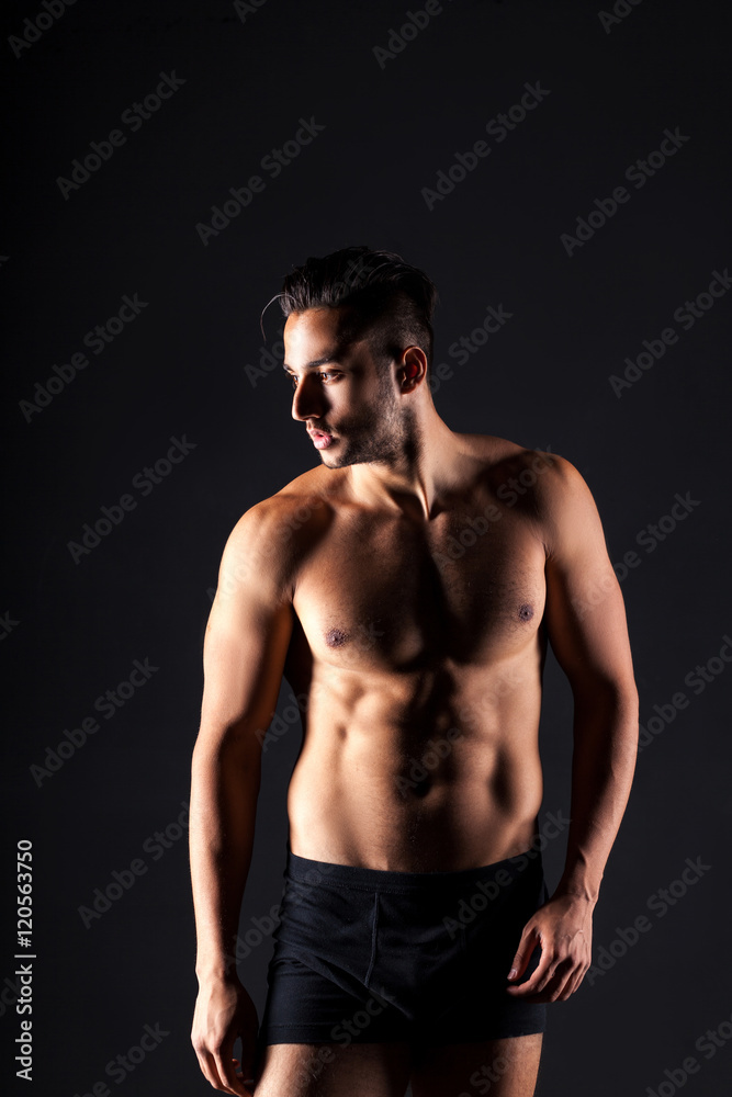 Sexy and expressive shirtless male model flirting against black