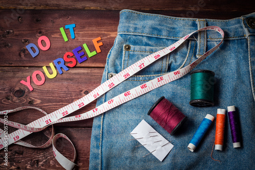 jeans and measuring tape and needle and many color threads on wo