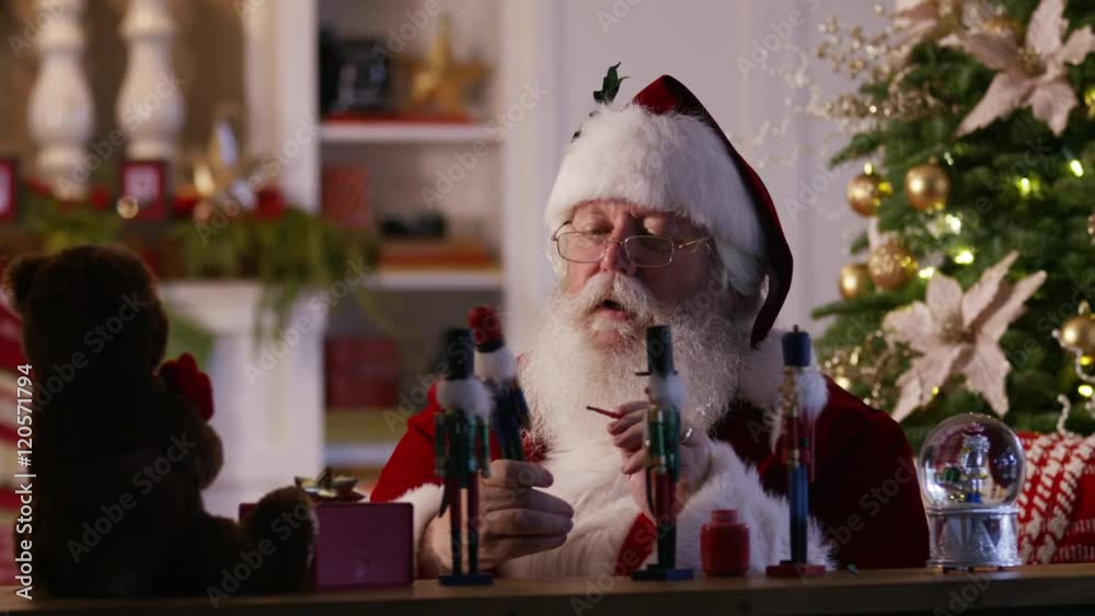 Santa Claus painting toys in workshop