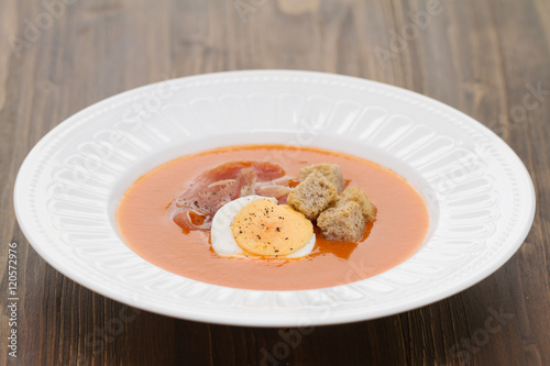 tomato cold soup with egg and jamon on white dish