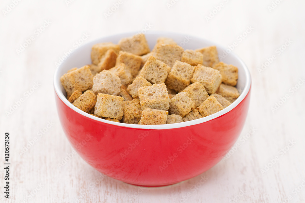 croutons in red bowl on white wooden background croutons in red bowl on white wooden background