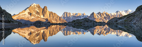 Panorama of Alps mountain range, sunset lights, reflection in lake