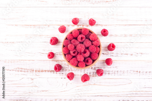 Fresh raspberries in bowl on white wooden background. Compositions of summer berries. Flat lay. Top view. Copy space