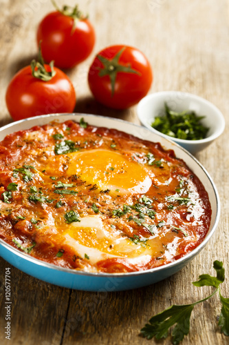 Fried eggs with tomatoes, spices and herbs