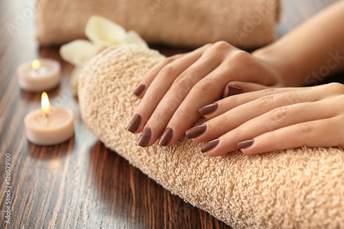 Fototapeta Naklejka Na Ścianę i Meble -  Female hands with brown manicure on towel