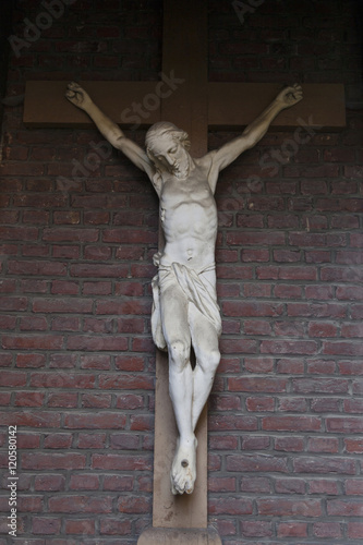 statue of jesus on cross against red brick wall