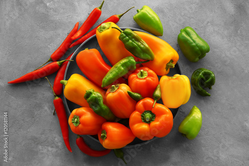 Slika na platnu Fresh peppers in bowl on color background