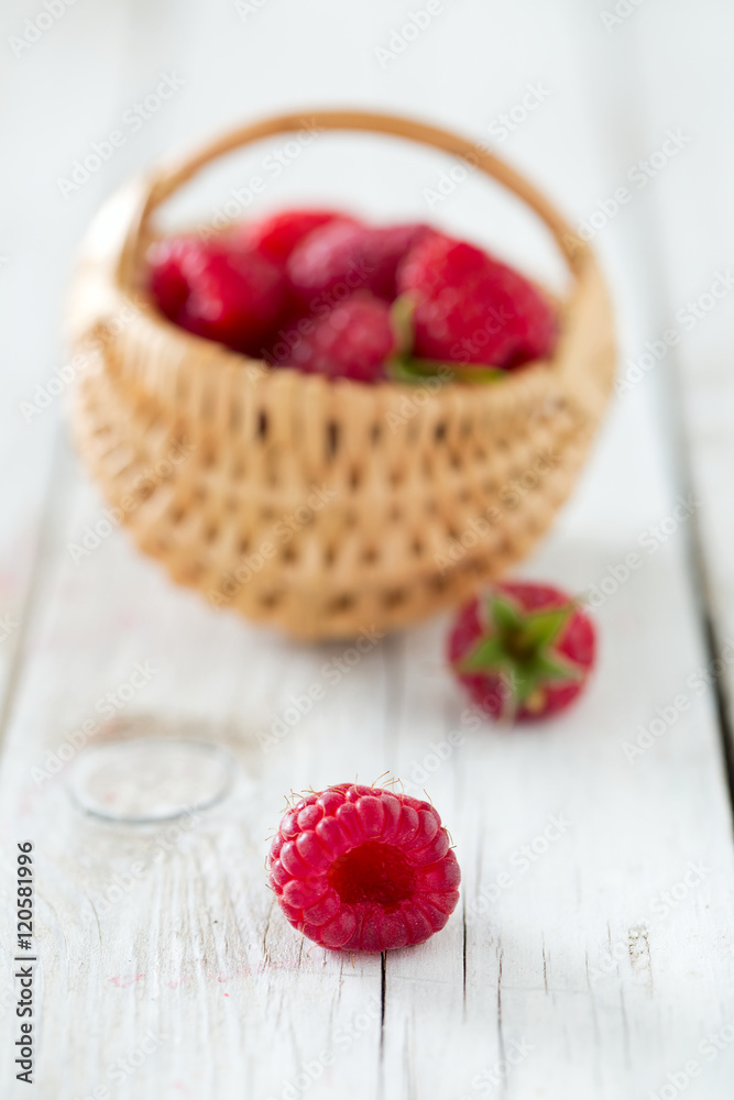 raspberries in a basket on wooden surface raspberries in a basket on wooden surface