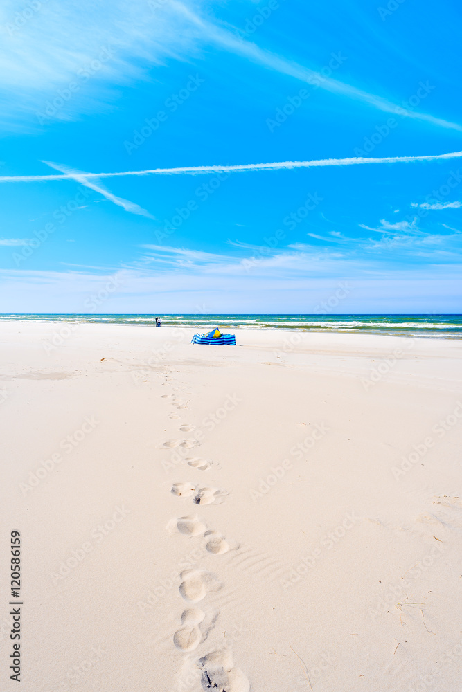 Footprints on sandy beach with windbreaker in distance in Debki village, Baltic Sea, Poland