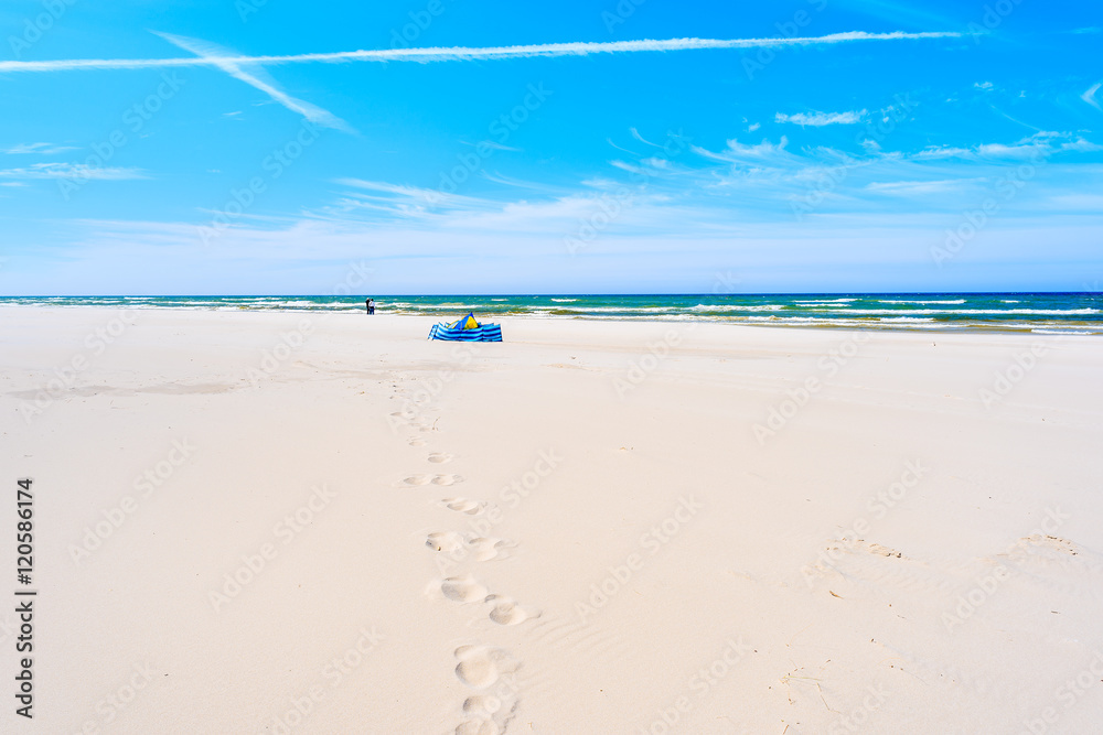 Footprints in sand on Debki beach with windbreaker in distance, Baltic Sea, Poland