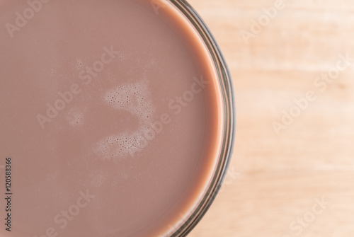 Glass of chocolate milk on a wood table.