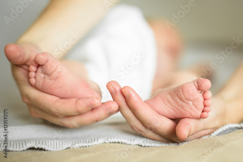 Маленькие ножки новорожденного в руках мамы