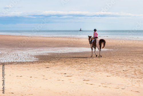 Girls ride a horse on the beach in morning.