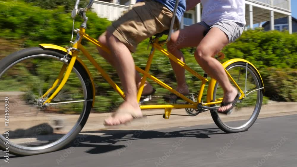 Couple riding tandem bicycle together in coastal vacation community
