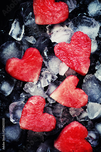 Red sweet watermelon hearts on crushed ice, dark food background