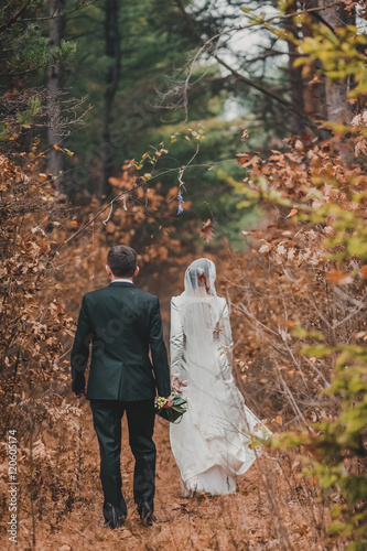 happy bride and groom walking in the autumn forest. Red leaves.  © nataliakabliuk