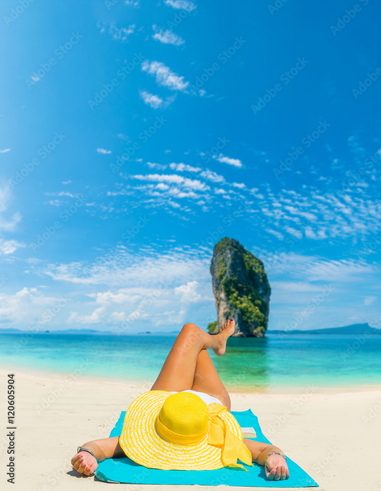 Woman lies on the beach with yellow hat