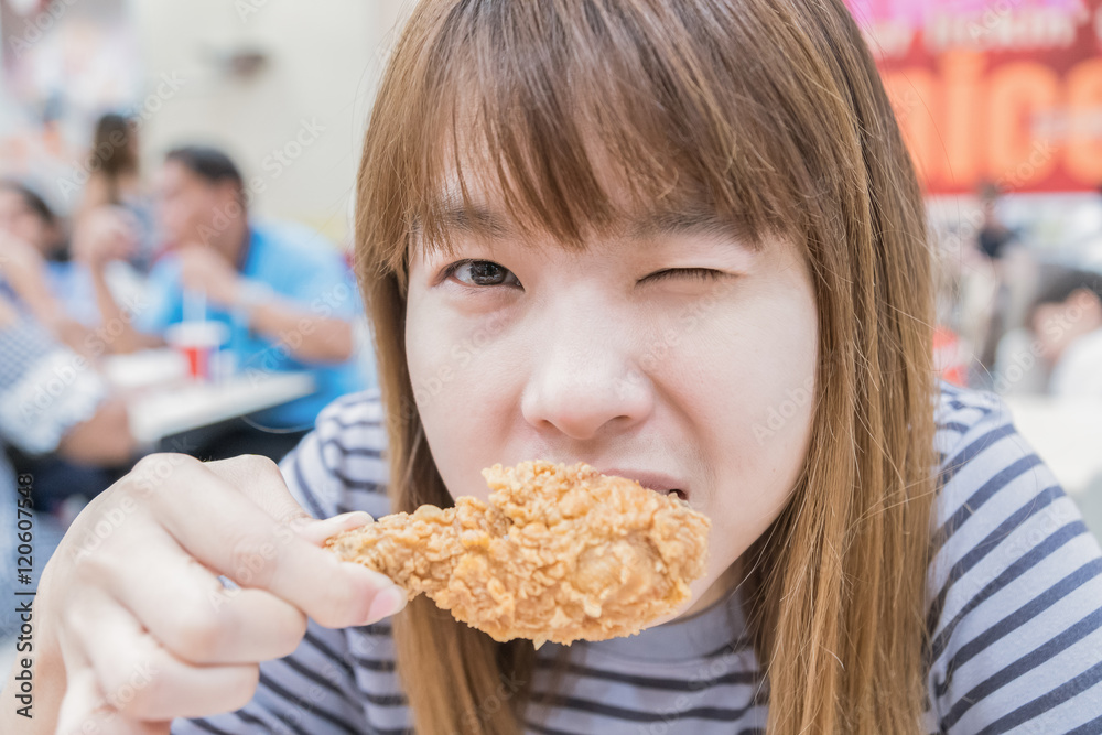 Young happy woman holding and eating fries chicken Young happy woman holding and eating fries chicken
