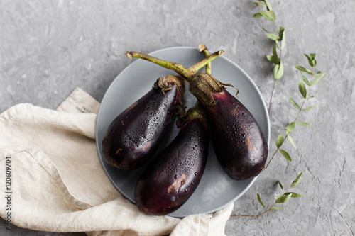 Purple eggplant on a plate on a gray background