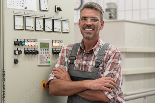 Technician standing on control console of sewage sludge drying machine in water purification plant