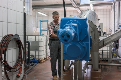 Technician maintaining sewage sludgy dryer in machine room of wastewater treatment plant