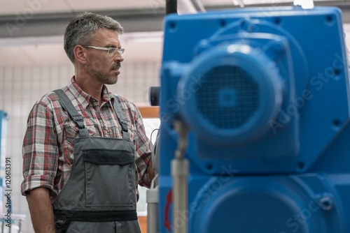 Technician maintaining sewage sludgy dryer in machine room of wastewater treatment plant