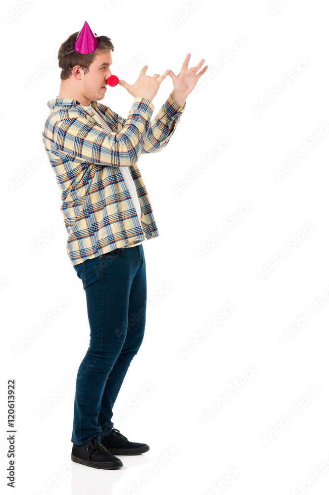 Handsome man clown isolated on white background. Teen boy with crazy look making faces and wearing red nose. Handsome man clown isolated on white background. Teen boy with crazy look making faces and wearing red nose.