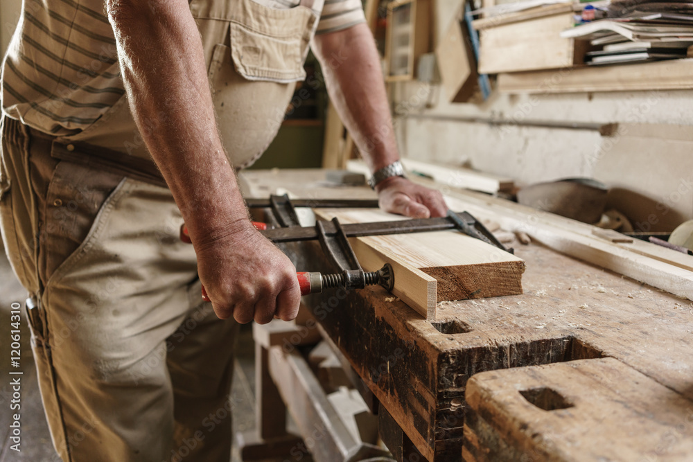 Craftsman in his carpentry workshop pressing wooden workpiece wi Craftsman in his carpentry workshop pressing wooden workpiece wi