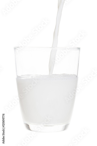 Pouring milk in clear glass isolated on white background with cl