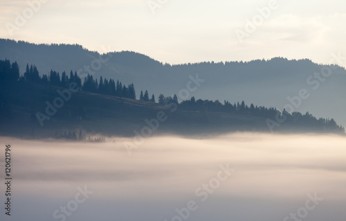 Fog over mountain range in sunrise light. © Dmytro Kosmenko