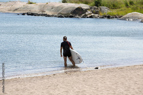 An unidentified man is carrying a surf board after the run in the ocean.
