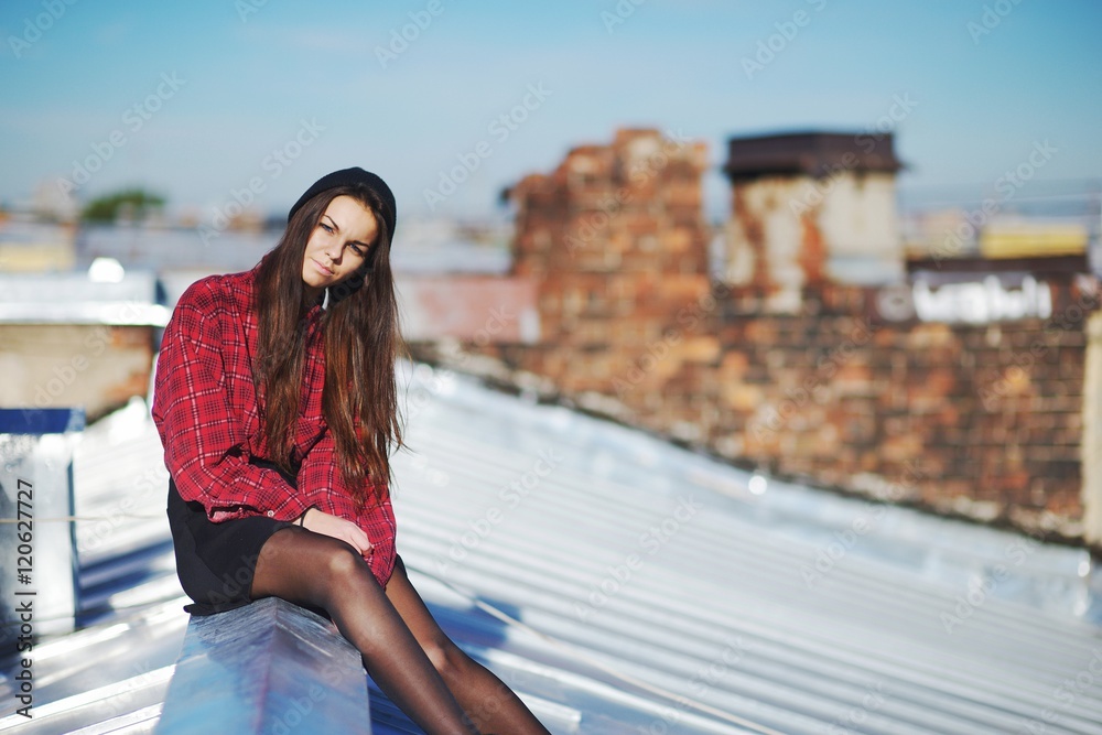 Young pretty girl sitting on a iron roof.