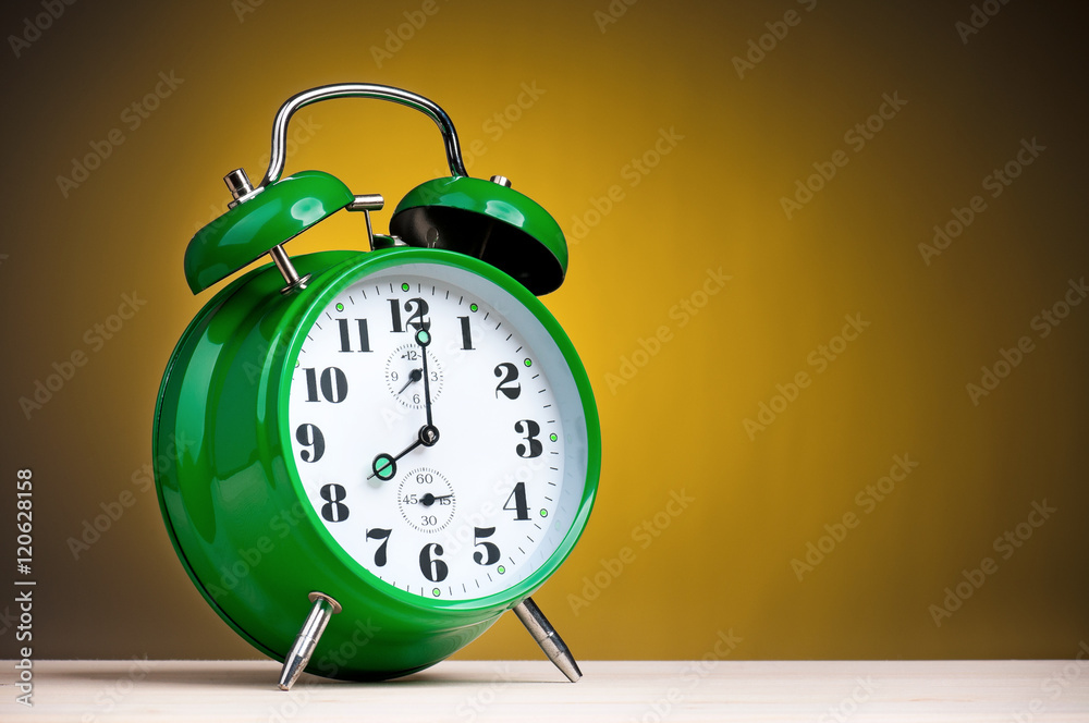 Retro alarm clock on yellow background. Green alarm-clock old style on wooden table. Retro alarm clock on yellow background. Green alarm-clock old style on wooden table.