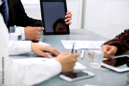Group of business people at meeting, close up. Boss pointing into tablet computer monitor