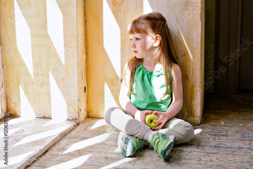 red-haired girl with an apple sitting by the window