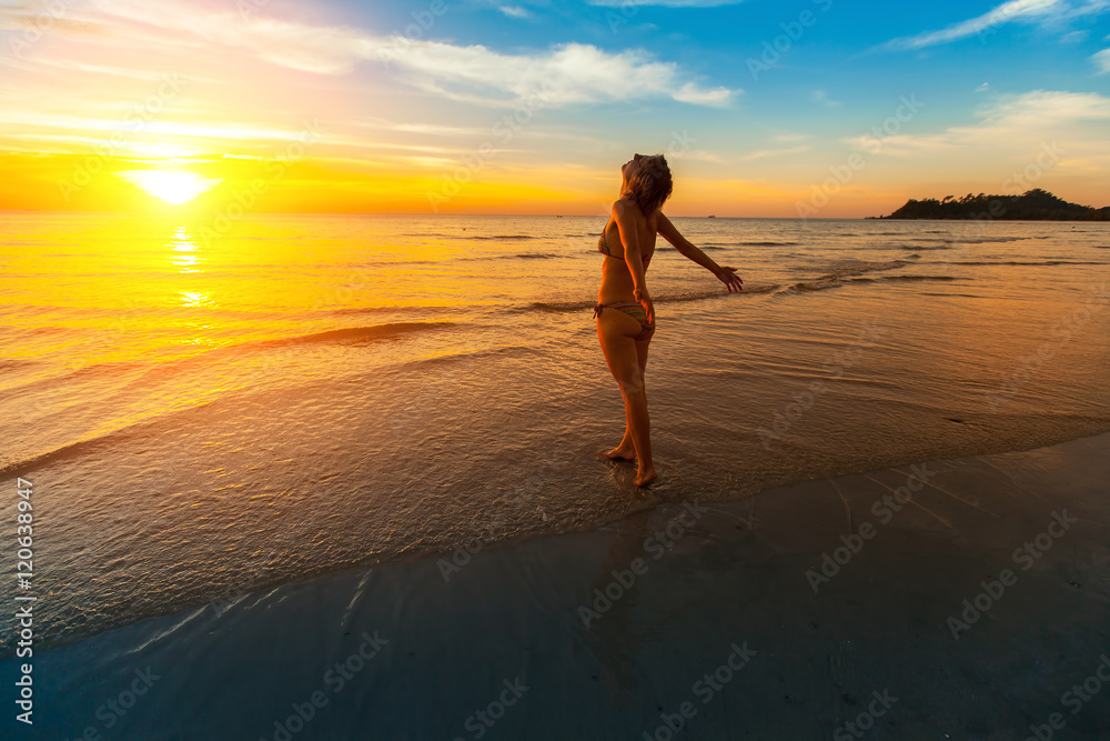Young woman worth towards the beautiful sunset on the sea beach.