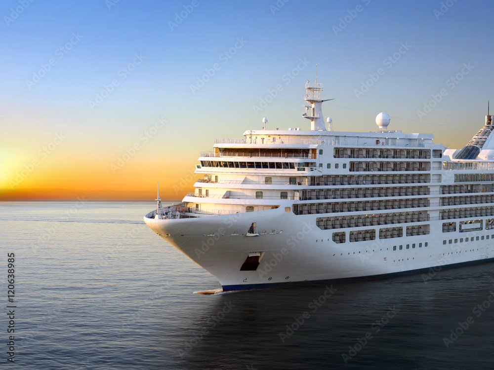 Luxury cruise ship sailing from port on sunset 