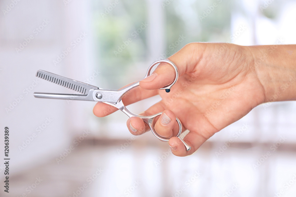 Hairdresser holding professional scissors on blurred background Hairdresser holding professional scissors on blurred background