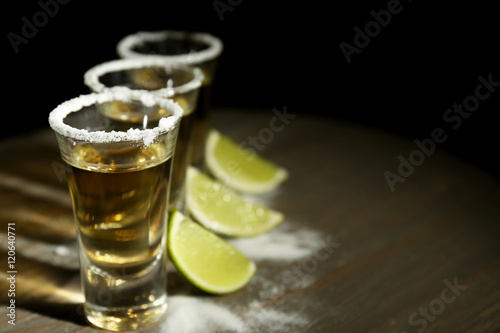 Gold tequila shots with lime and salt on wooden table