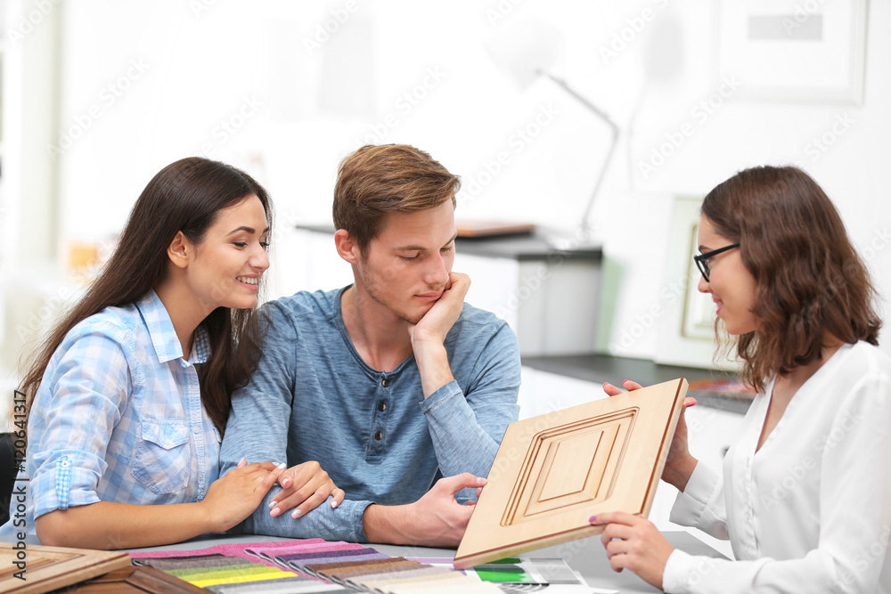Beautiful young couple talking with designer in office Beautiful young couple talking with designer in office