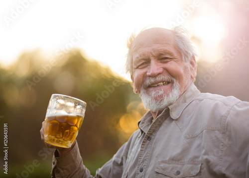 Пенсионер пьет пиво на природе photo