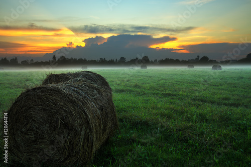 Туманный закат в поле со стогами сена