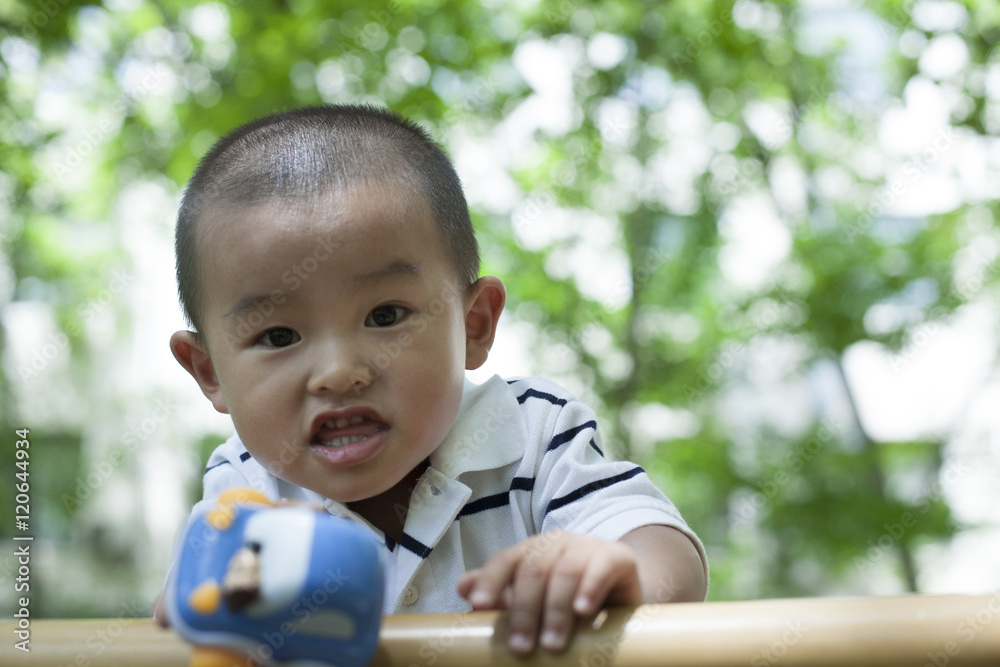 Cute Chinese baby boy playing on a bench in woods Cute Chinese baby boy playing on a bench in woods