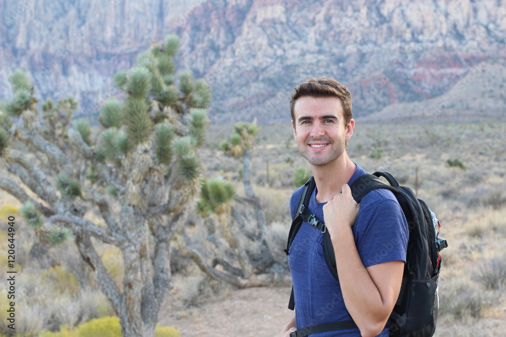Grand Canyon travel - happy man mountain hiker with backpack on the rocky dry mountains Grand Canyon travel - happy man mountain hiker with backpack on the rocky dry mountains